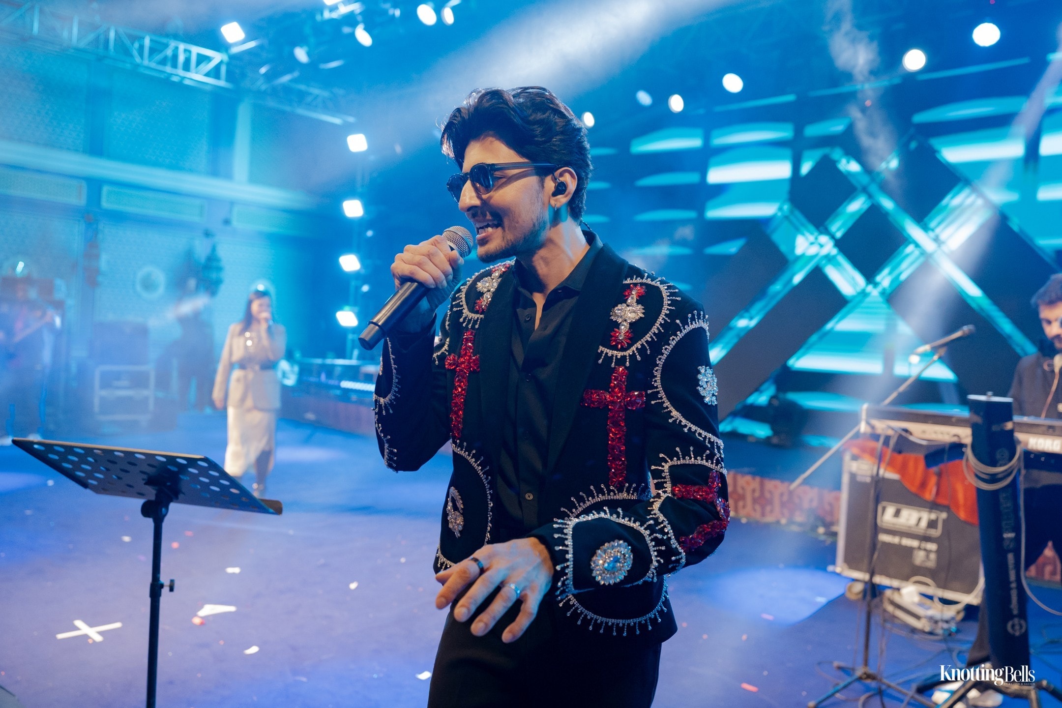Live singer performing on stage with blue spotlights at sangeet